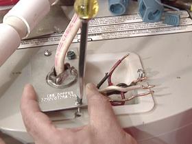 Plumber refastens electrical plate on a conventional water heater